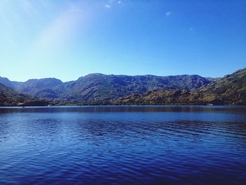 Scenic view of lake and mountains against clear blue sky