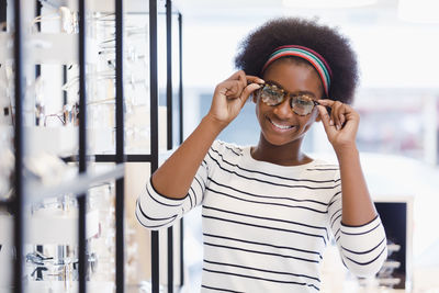 Portrait of smiling young woman standing against wall