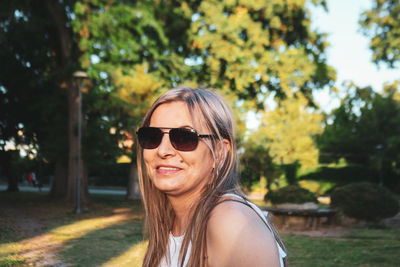 Portrait of young woman wearing sunglasses against trees