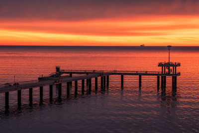 Pier over sea against sky during sunset