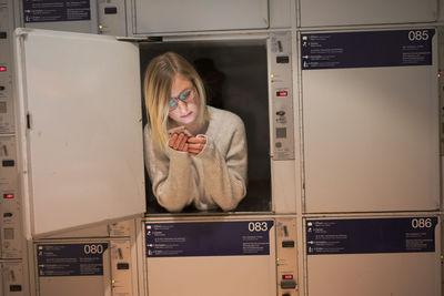 Young woman using phone in locker