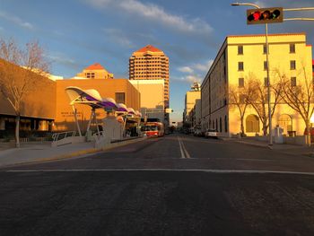 Road by buildings in city against sky