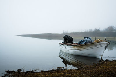 Boat moored on shore against sky