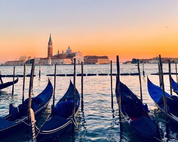 Boats moored in canal at sunset