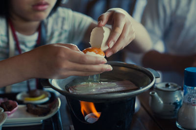 Person cooking egg in cooking pan