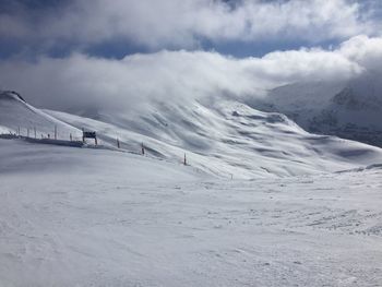 Scenic view of snowcapped mountain against cloudy sky