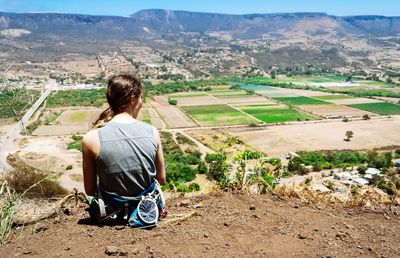 Rear view of woman sitting on land