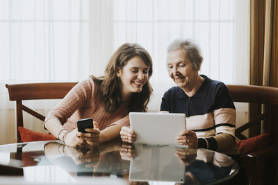 Grandmother teaching her granddaughter something on the tablet