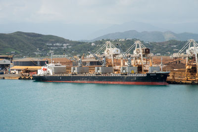 Boats moored at harbor by sea against sky