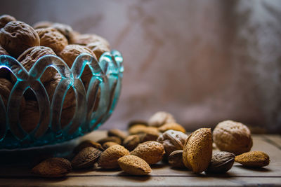 Walnuts and almonds in a blue glass bowl on a rustic wooden table