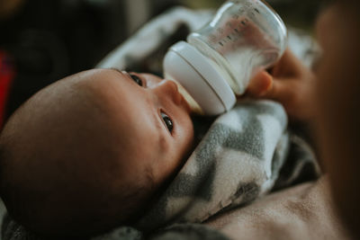 Close-up mother feeding baby milk with bottle