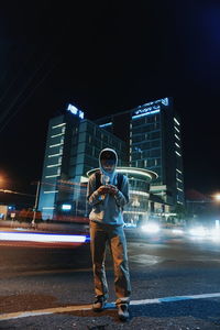 Full length of young woman standing on road at night
