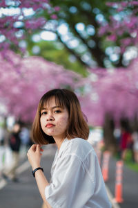 Portrait of woman standing against pink trees