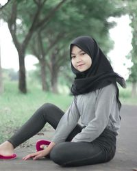 Young woman sitting on plant against trees