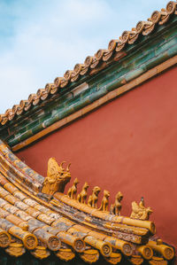 Low angle view of sculptures on roof of building against sky