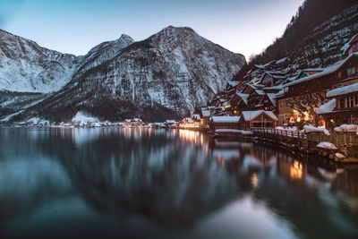Snowcapped mountain and houses reflecting on lake in town