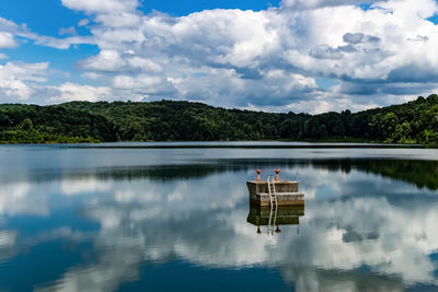 Floating platform amidst lake by mountain against sky