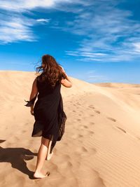 Rear view of woman walking in desert