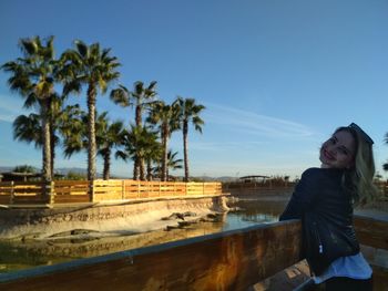 Woman standing by palm trees against sky