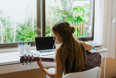 Midsection of woman using laptop at home