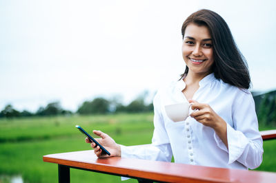 Smiling young woman using smart phone