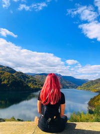 Rear view of woman looking at lake against sky