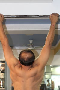 Close-up rear view of man doing pull ups