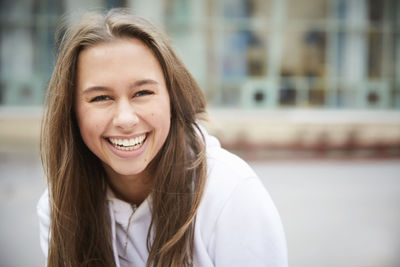 Portrait of smiling teenage girl sitting in schoolyard