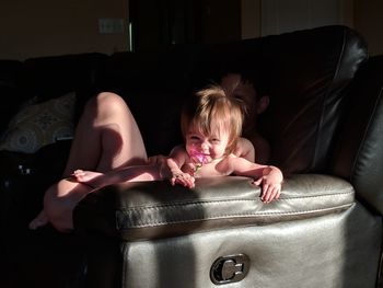 Siblings relaxing on sofa at home