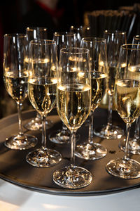 Champagne glasses on tray illuminated by soft glow from background. vertical.