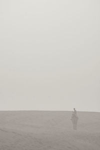 Man standing on sea shore against clear sky