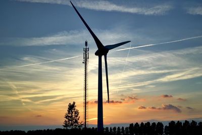 Low angle view of wind turbines on field