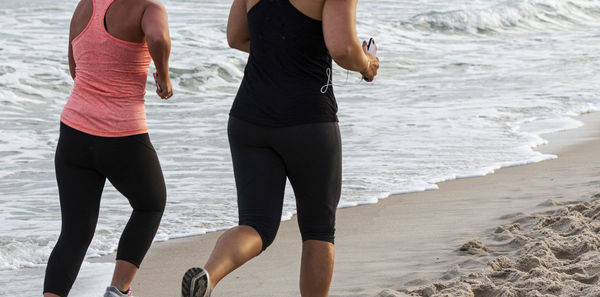 Midsection of women running on beach