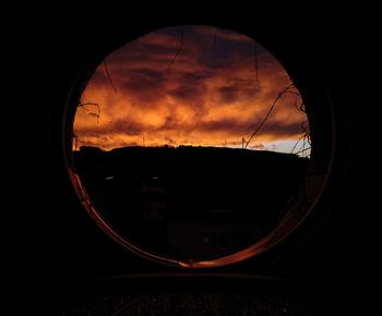 Silhouette landscape seen through window during sunset