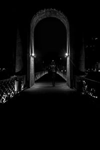 Rear view of man walking on illuminated building at night