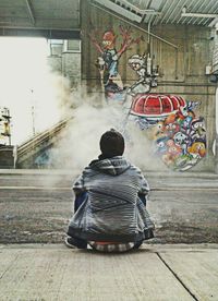 Woman standing by graffiti wall