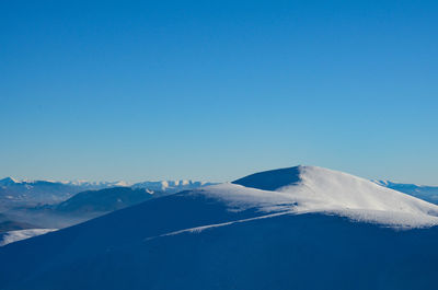 Scenic view of snowcapped mountains against clear blue sky