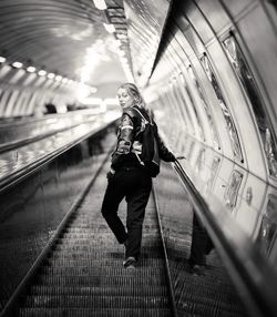 Full length portrait of woman standing on moving walkway