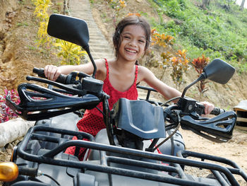 Portrait of cute cheerful girl sitting on quadbike