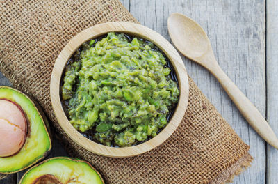 High angle view of avocado with paste in bowl on table