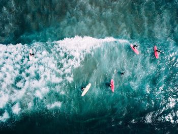Aerial view of people surfboarding on sea