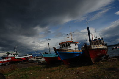 Boats in river against cloudy sky