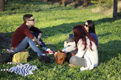 Friends talking while sitting on grass