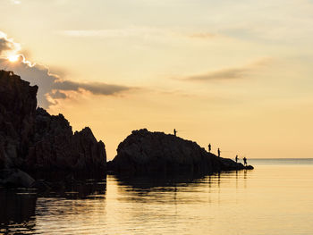 Silhouette of fishermen on shore at sunset