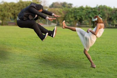 Bride kicking groom on grassy field