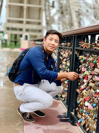 Portrait of young man with love locks on bridge railing