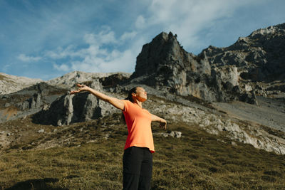 Hiker standing with arms outstretched against mountain at cares trail in picos de europe national park, asturias, spain