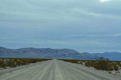 Empty road along landscape against sky