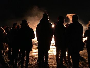 Silhouette people standing against bonfire at night