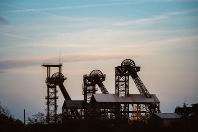 Low angle view of crane against sky at sunset
